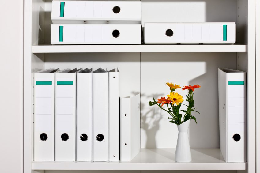 Shelf with white folders and flower vase